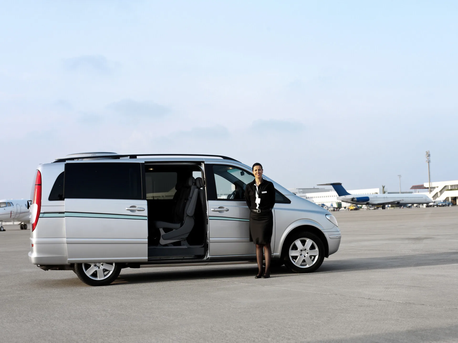 行李太多怎麼辦?選對機場接送車型才不怕塞不下! - 機場接送首選、24H 專車預約、全台接送服務推薦|奔旅派車 - 機場接送首選、24H 專車預約、全台接送服務推薦|奔旅派車 司機正在協助乘客搬運多件大型行李至九人座廂型車,對應行李量大或多人出行的接送需求。