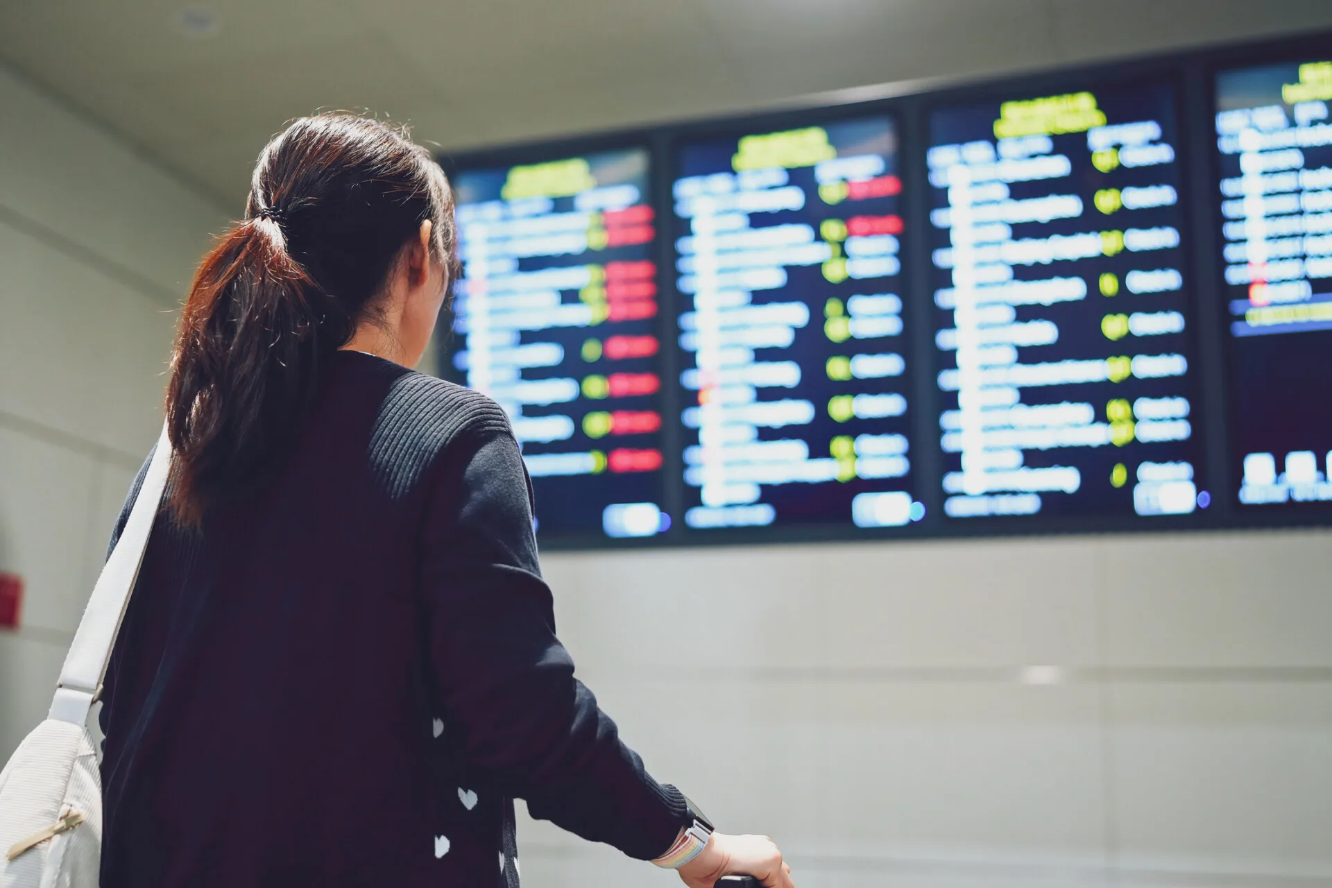 A Traveler Checking Flight Information at an Airport Departure Board - 機場接送首選、24H 專車預約、全台接送服務推薦|奔旅派車 - 機場接送首選、24H 專車預約、全台接送服務推薦|奔旅派車