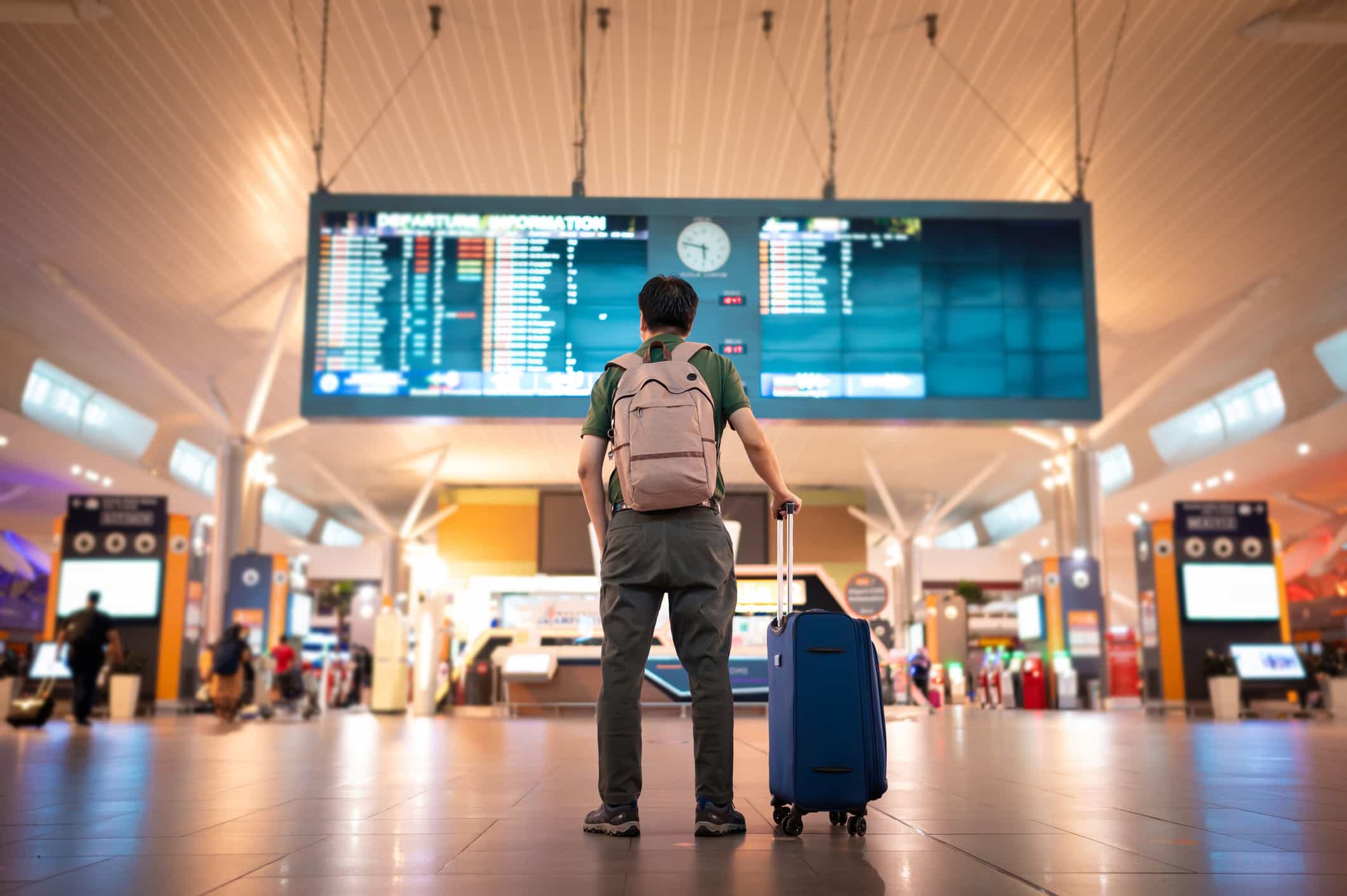 旅客在國際機場查詢航班資訊,規劃接送時機 - 機場接送首選、24H 專車預約、全台接送服務推薦|奔旅派車 - 機場接送首選、24H 專車預約、全台接送服務推薦|奔旅派車 一位男遊客站在國際機場,正查看航班的到達與離開公告牌,準備安排行程與接送時間。