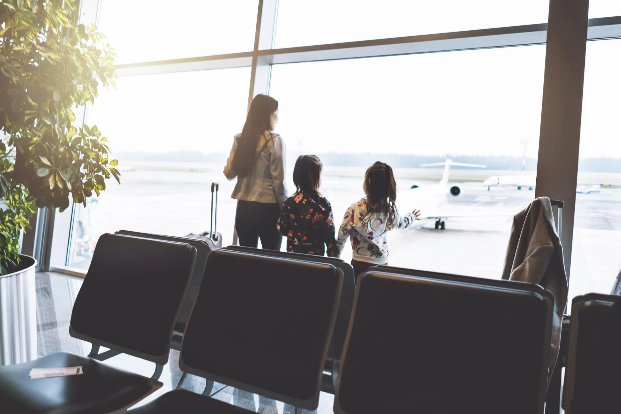 一家三口在機場航廈走道的背影，推著行李準備出國旅行