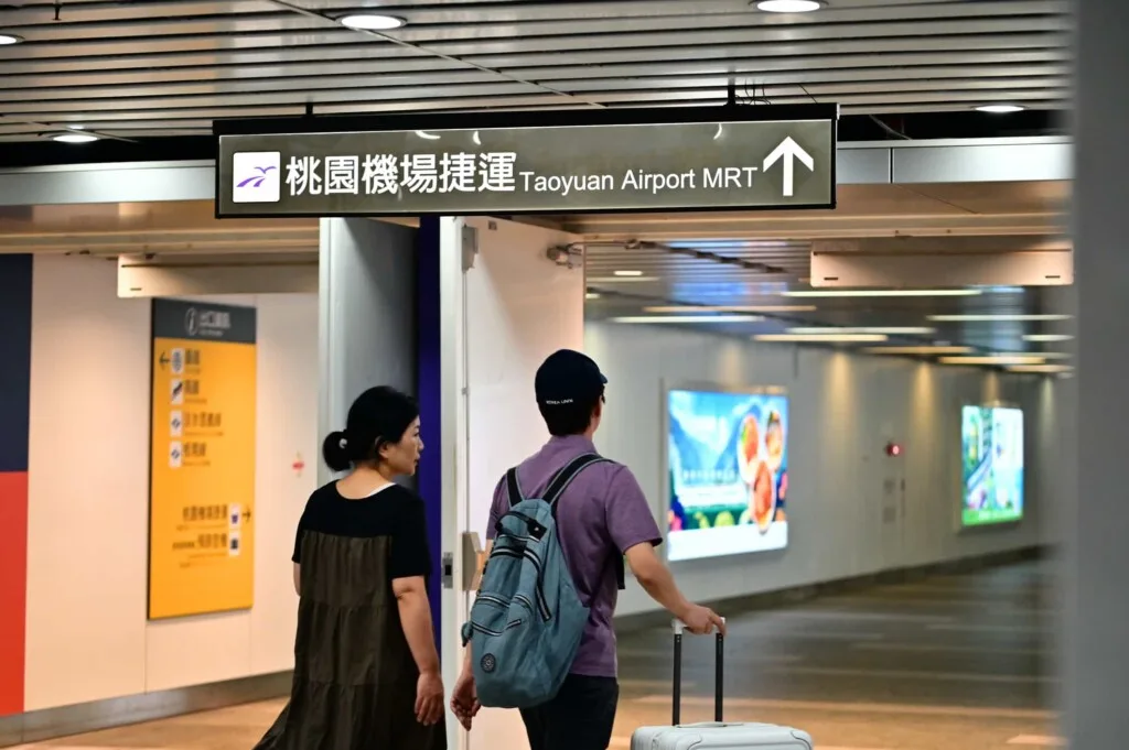 第一次來台灣的旅客拖著行李,在機場尋找接送服務進市區