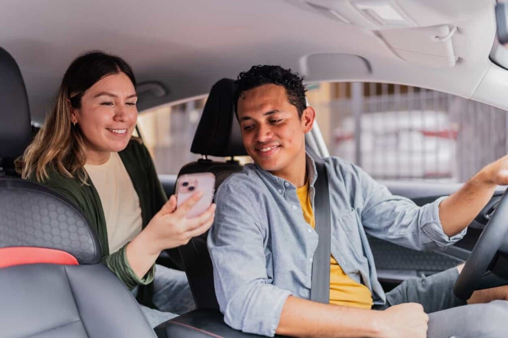 乘客向司機展示手機資訊協助導航或確認行程，呈現友善互動的機場接送服務。